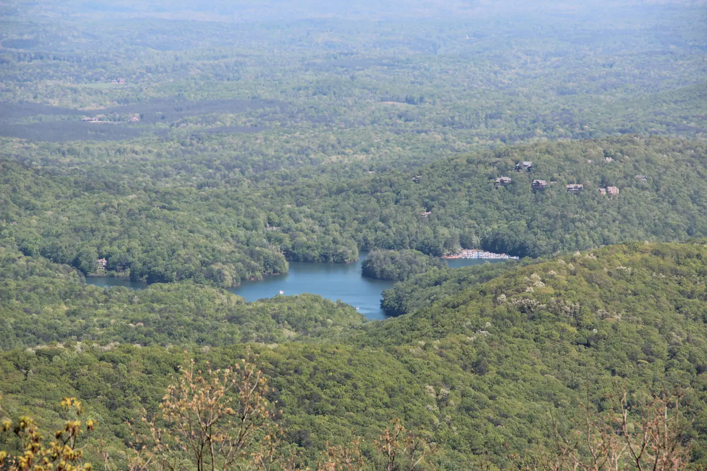 A high view over continuous green forest with the blue arms of a lake winding between wooded ridges